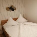 Ein Schlafzimmer mit Bett, weißen Kissen und einer Wanddekoration.