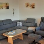 Wohnzimmer mit grauem Sofa, Sessel und Holztisch