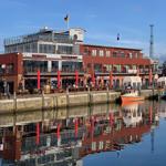 Hafenrestaurant mit Terrasse und Booten im Wasser.
