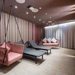 Raum mit zwei hängenden Sitzmöbeln und Liegen. Wandverkleidung mit Streifenmuster.