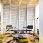 Terrasse mit Tischen und Stühlen unter Holzverkleidung.