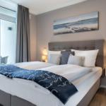 Schlafzimmer mit Balkon, Bett und Wandbild.