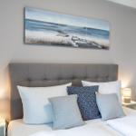 Schlafzimmer mit Bett, Kissen und Wandbild an der Wand.