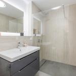 Badezimmer mit Dusche, Waschbecken und Spiegel.