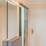 Hausgang mit Spiegelschrank, Glastür und weißer Tür mit Griff.