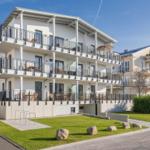 Modernes Mehrfamilienhaus mit Balkonen und Grünfläche.