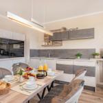 Küche mit Esstisch, modernen Schränken und Küchengeräten.