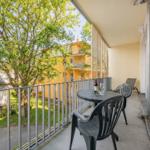 Terrasse mit Tisch, Stühlen und Blick auf einen Garten und gelbes Gebäude.