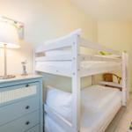 Zimmer mit Doppelstockbett, Schrank und Lampe.