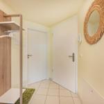 Flur mit Kleiderschrank, Spiegel und zwei Türen.