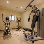 Fitnessraum mit Laufband, Fahrrad und Kraftstation.