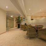 Wohnbereich mit Sitzgruppe, Pflanze und Glaswand. Fliesenboden und Wandfliesen.