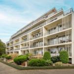 Modernes Mehrfamilienhaus mit Balkonen und gepflegtem Gartenbereich.