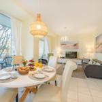 Esszimmer mit Tisch, Stühlen und Blick auf Balkon. Wohnzimmer mit Sofa und Fernseher.