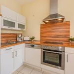 Küche mit weißen Schränken, Holzoberflächen und Edelstahlgeräten.