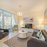 Wohnzimmer mit Sofa, Sessel und TV. Durchgang zur Terrasse.