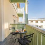 Terrasse mit Tisch und Stühlen, Frühstückszubehör und Blick auf Gebäude und Bäume.