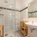 Badezimmer mit Dusche, Waschbecken und Spiegel
