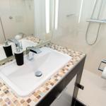 Badezimmer mit Waschbecken, Spiegel und Dusche.