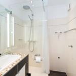 Badezimmer mit Dusche, Waschbecken und Spiegel.