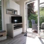 Ein Raum mit TV, Schrank und Balkonansicht durch Glastüren.