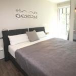 Schlafzimmer mit Bett, Wanddekoration und Fenster zur Aussicht.