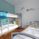 Zimmer mit Doppelstockbett und Einzelbett, Wandregal mit Büchern und Stofftieren.