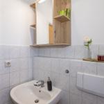 Badezimmer mit Waschbecken, Spiegelschrank und Keramikfliesen.