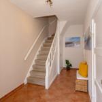 Hausflur mit Treppe, Sitzbank und Wandbildern.