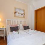 Schlafzimmer mit Bett, Nachttisch, Lampe und Wandbild.