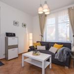 Wohnzimmer mit Sofa, Tisch und Fenstern.