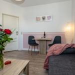 Wohnzimmer mit Sofa, Esstisch, Lampe und Blumen.