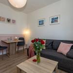 Wohnzimmer mit Sofa, Tisch und Stühlen, Wandbilder und Blumen auf dem Tisch.