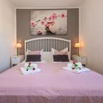 Schlafzimmer mit Bett, Nachttischen und Wandbild. Auf Bett liegen Getränke und Handtücher.