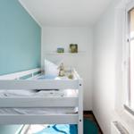 Ein Schlafzimmer mit Doppelbett, Fenster und Bücherregal.