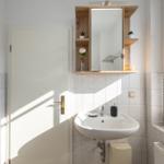 Badezimmer mit Waschbecken, Spiegelschrank und Fenster