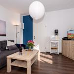 Wohnzimmer mit Sofa, Couchtisch, Fernseher und Küchenzeile.