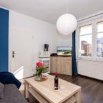 Wohnzimmer mit Sofa, Couchtisch und Fernseher. Fenster mit Blick auf Stadt.