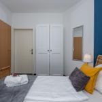 Schlafzimmer mit Bett, Kleiderschrank und Spiegel an der Wand.
