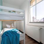 Zimmer mit Doppelstockbett, Fenster und Heizkörper.