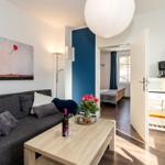 Wohnzimmer mit Sofa, Couchtisch und Gemälde. Durchgang zur Schlafzimmer.