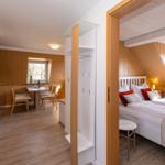 Schlafzimmer mit Doppelbett und angrenzender Essnische mit Tisch und Stühlen.