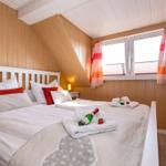 Schlafzimmer mit Dachschrägen, Bett mit Kissen und Flaschen auf Handtüchern.