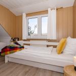 Zwei Betten mit weißen Laken und bunten Decken unter Holzwänden und Dachschrägen.