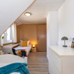 Zimmer mit zwei Betten, Schrank und Fenster unter Dachschräge.
