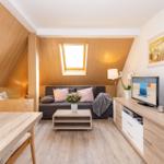 Wohnbereich mit Sofa, TV und Essbereich unter Holzdecke.