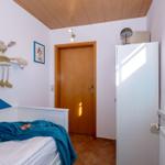 Ein Schlafzimmer mit Bett, Kleiderschrank und Fenster mit Jalousie.
