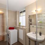 Badezimmer mit Waschmaschine, Spiegel und Dusche.