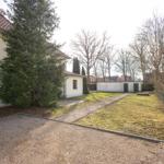 Haus mit Garten, Kiesfläche und Bäumen im Hintergrund.