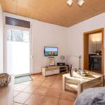 Wohnzimmer mit Fernseher, Tisch und Fenster. Blick in benachbarte Räume.